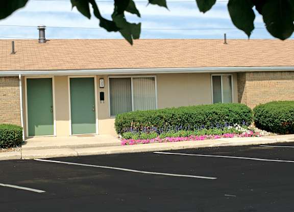 A building with a brown roof and a parking lot in front.