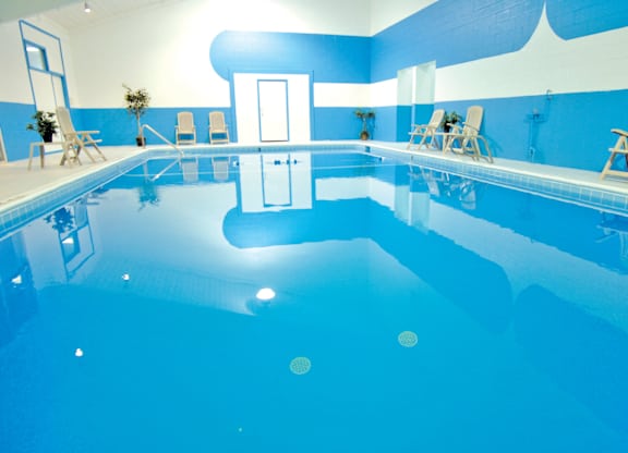 A large indoor swimming pool with a blue tint.