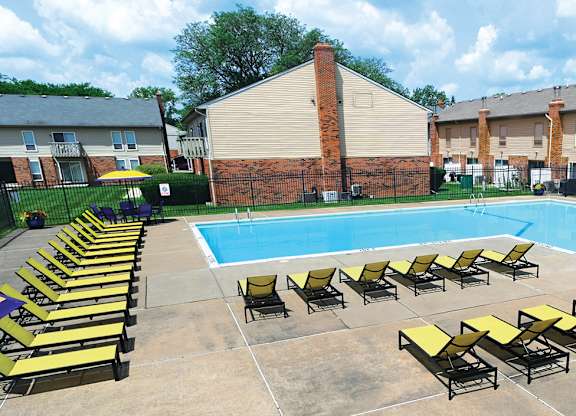 A pool surrounded by sun loungers and a brick building.
