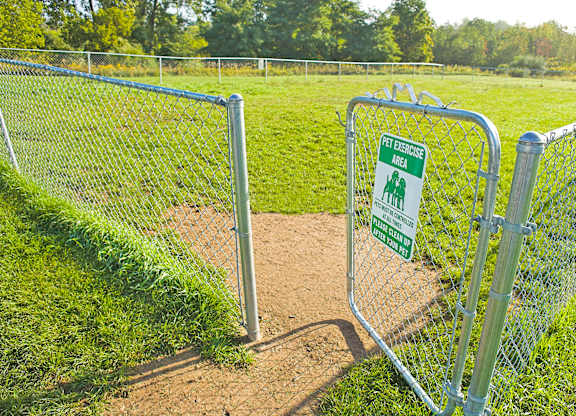A green sign on a fence that says "Pet Exercise Area".