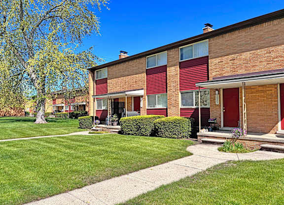 A red and brown building with a green lawn in front.
