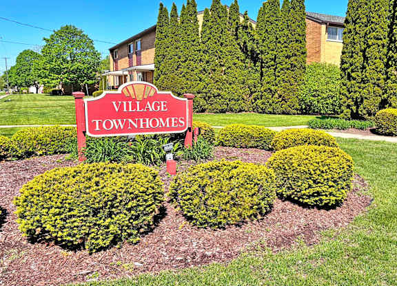 A sign that says Village Townhomes in front of a building.
