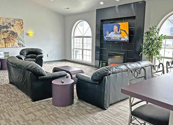 A living room with a television and black leather furniture.
