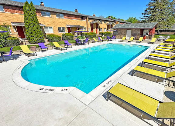 A swimming pool surrounded by yellow sun loungers.