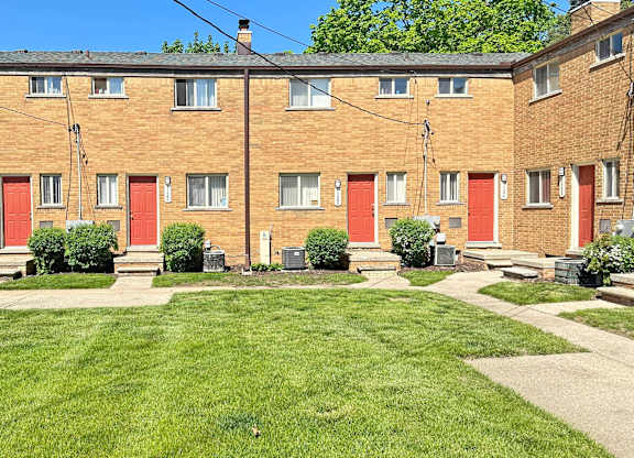 A large grassy area in front of a brick building with red doors.