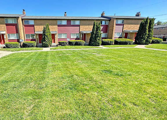 A grassy area in front of a building with red and beige exterior.