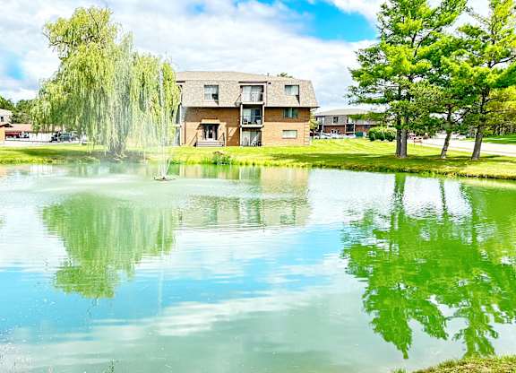 A serene lake in front of a building surrounded by trees.