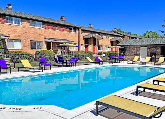 A swimming pool with sun loungers and a building in the background.