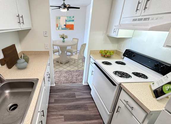 A kitchen with a stove, sink, and cabinets.