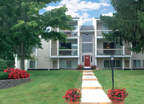 A building with a red door and a walkway with red flowers in front.