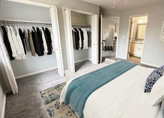 A bedroom with a bed, pillows, a wardrobe, and a mirror.