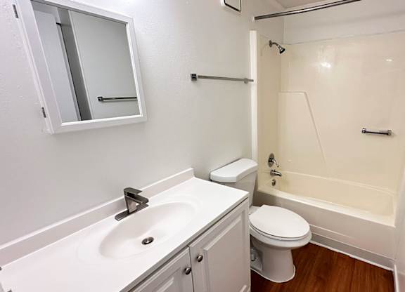 A white bathroom with a toilet, sink, and bathtub.