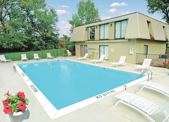 A pool with chairs and a house in the background.