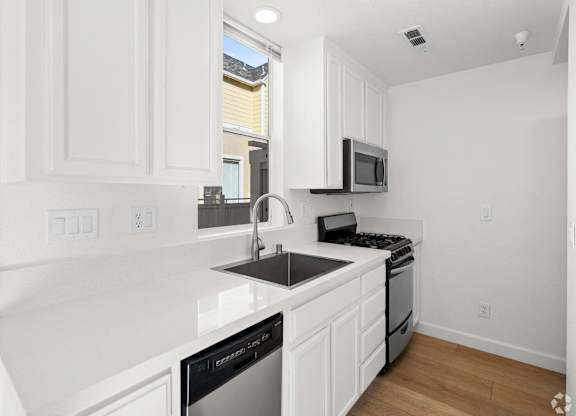 A kitchen with white cabinets and black appliances. at Westmont Place Townhomes Apartments, Santa Cruz, 95060