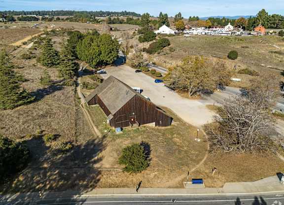 A large barn sits in the middle of a field with a road running in front of it at Westmont Place Townhomes Apartments, Santa Cruz, CA, 95060