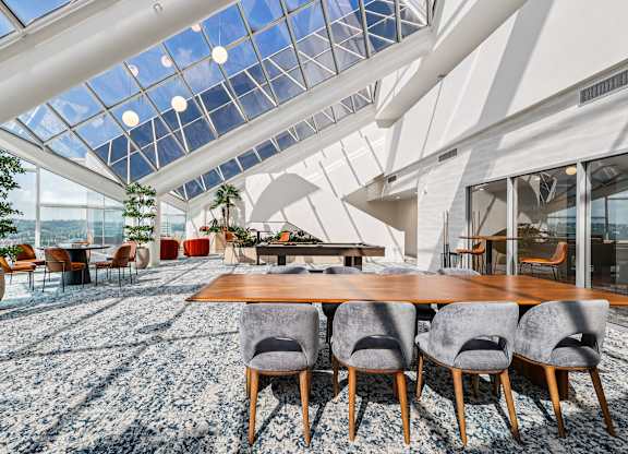 A modern dining room with a glass ceiling and a long wooden table at 7 West 7th Apartments, Ohio