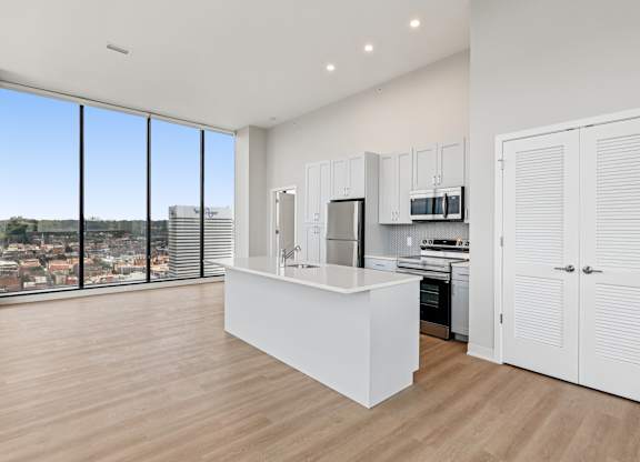 A kitchen with white cabinets and a large window overlooking a cityscape at 7 West 7th Apartments, Cincinnati, 45202