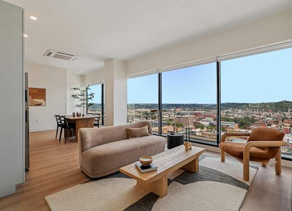 A living room with a couch, chair, and table with a view of the city at 7 West 7th Apartments, Ohio, 45202