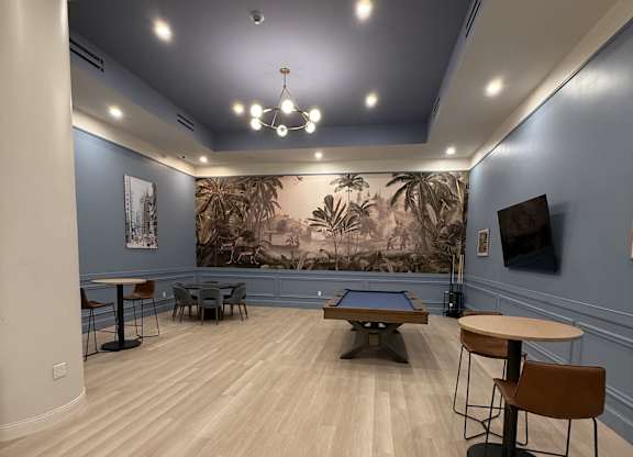 A room with a pool table and a wall mural of a jungle scene.