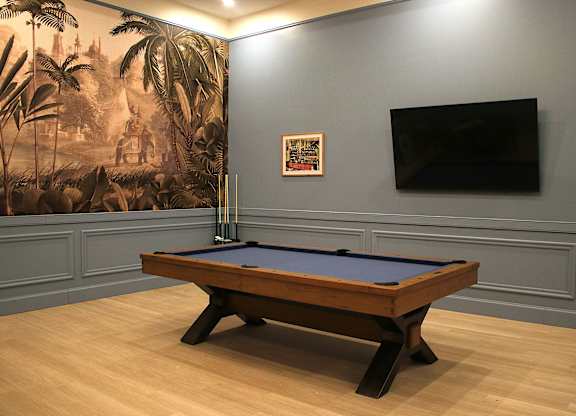 A pool table in a room with a jungle mural on the wall.