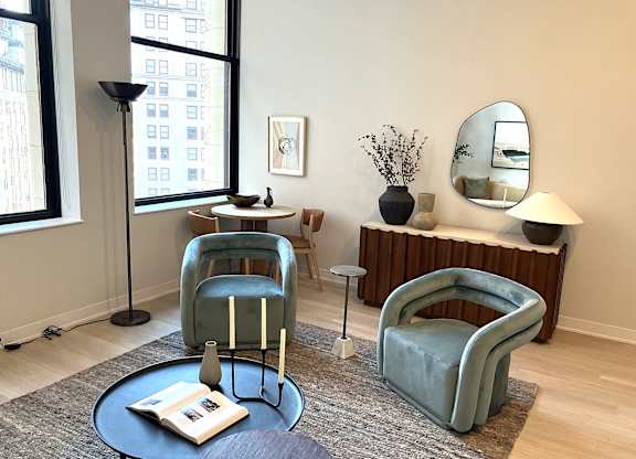 A living room with a blue chair and a round table with a book on it.