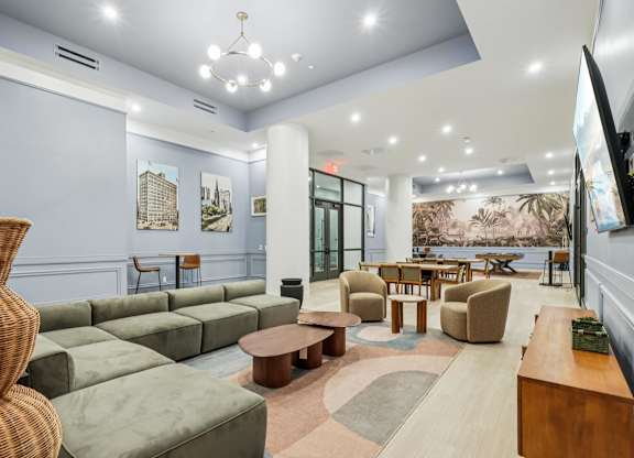 A spacious living room with a large wicker chair and a green sofa at LiveWell Apartments, Pittsburgh, Pennsylvania