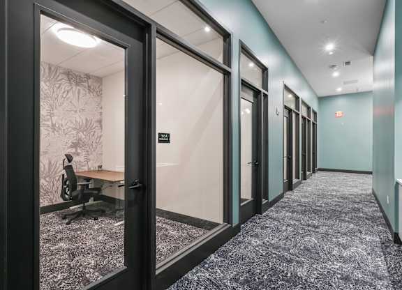 A long hallway with a carpeted floor and glass doors at LiveWell Apartments, Pittsburgh, PA