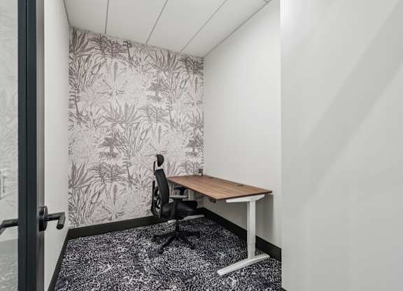 A small room with a desk and a plant pattern wallpaper. at LiveWell Apartments, Pittsburgh 15222