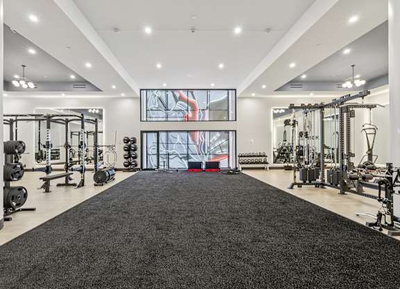 A spacious gym with a variety of equipment and a large mirror on the wall. at LiveWell Apartments, Pennsylvania
