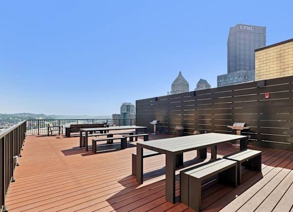A rooftop patio with wooden flooring and furniture at LiveWell Apartments, Pittsburgh, Pennsylvania