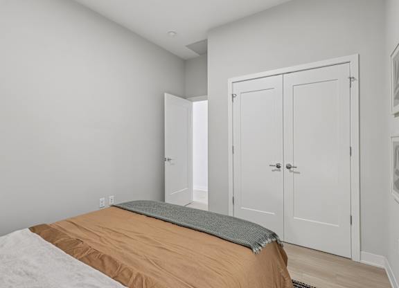 A bedroom with a bed, a mattress, and two white doors at LiveWell Apartments, Pittsburgh, PA, 15222