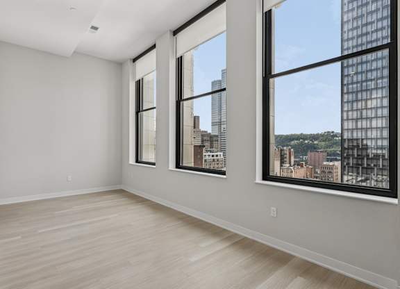 A large empty room with a view of the city through the windows at LiveWell Apartments, Pittsburgh 15222