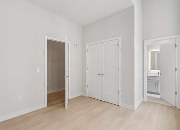 A white room with a wooden floor and three doors at LiveWell Apartments, Pittsburgh