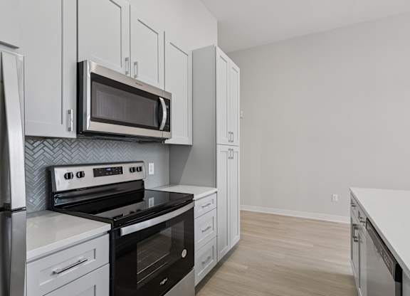 A kitchen with a stove, oven, microwave, and cabinets. at LiveWell Apartments, Pittsburgh 15222