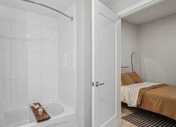 A white bathroom with a tub and a bed. at LiveWell Apartments, Pittsburgh