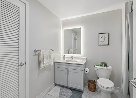 A white bathroom with a toilet, sink, and mirror at LiveWell Apartments, Pennsylvania