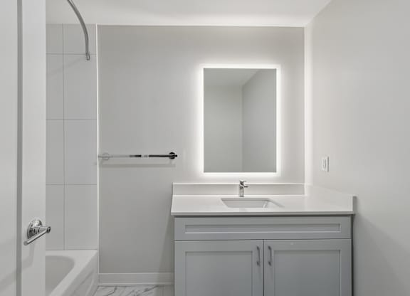 A white bathroom with a sink, mirror, and bathtub at LiveWell Apartments, Pennsylvania, 15222