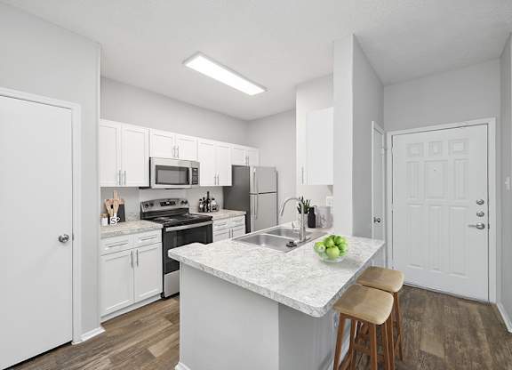 A kitchen with white cabinets and a marble island.