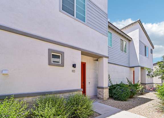 Baseline on 16th townhome with a red door and a small window on the side.