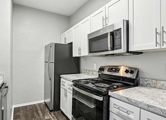 A kitchen with a black refrigerator, black stove, and white cabinets.
