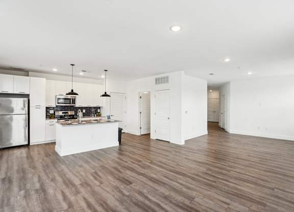 A modern kitchen with wooden floors and white cabinetry.