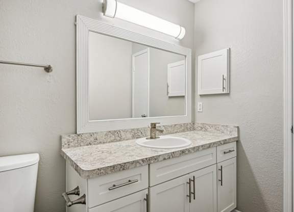 A bathroom with a marble countertop and white fixtures.