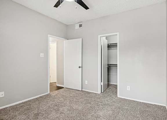 A room with a ceiling fan and two doors, one of which is open.