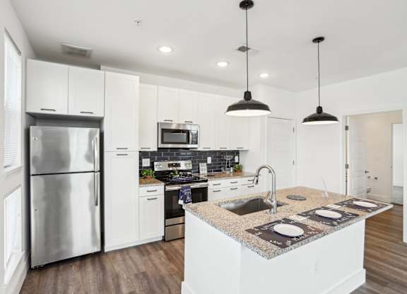 A modern kitchen with a granite countertop and stainless steel appliances.