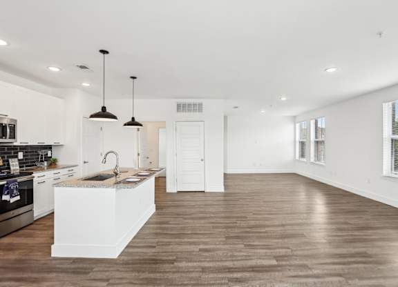 A modern kitchen with wooden floors and white cabinetry.