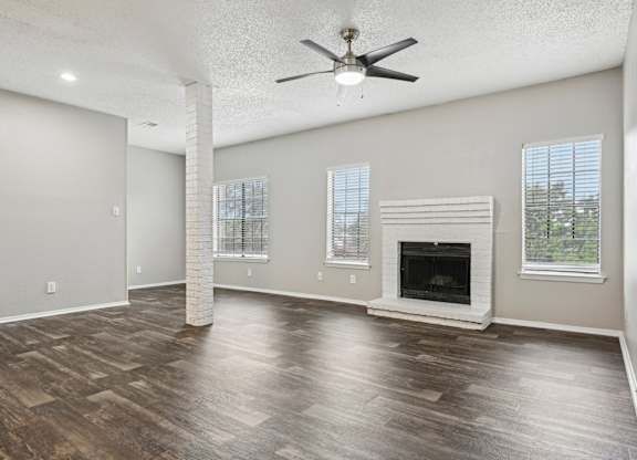 A spacious living room with a fireplace and wood flooring.