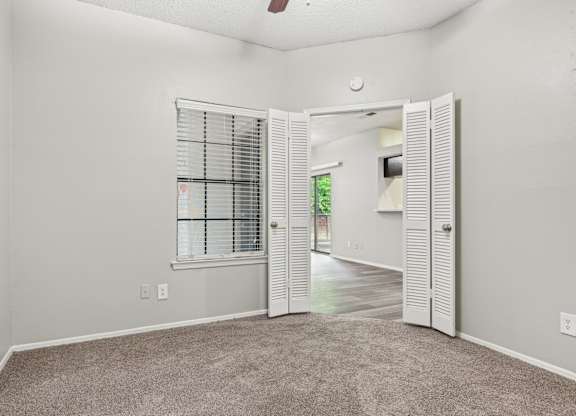 A room with a carpeted floor and a window with blinds.
