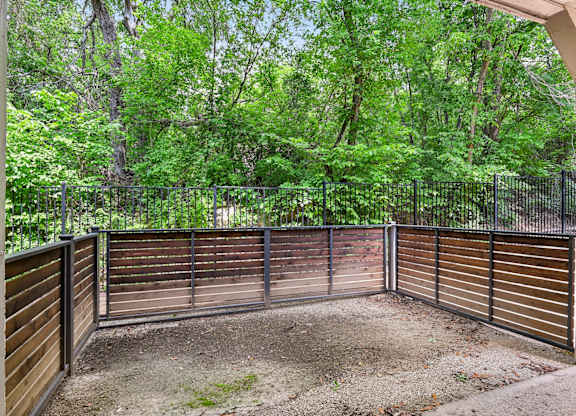 A backyard with a wooden fence and a dirt area in the middle.