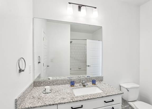A bathroom with a granite countertop and white fixtures.