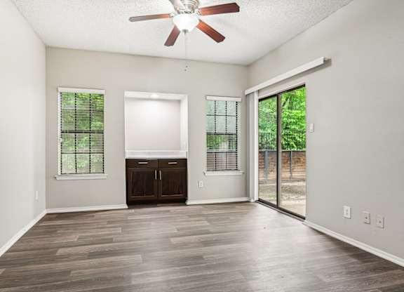 A room with a ceiling fan and sliding glass doors.